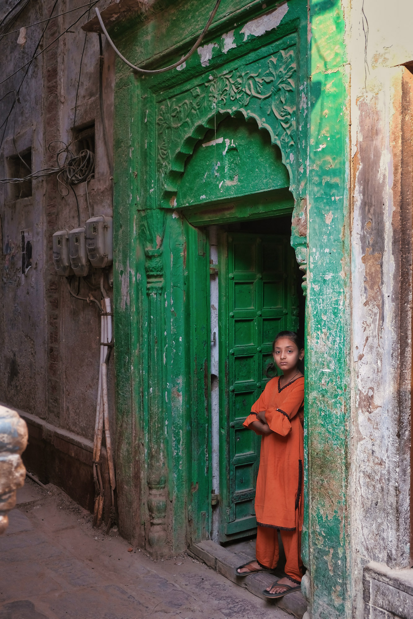 Bambina su una porta verde in un vicolo di Varanasi, Uttar Pradesh, India