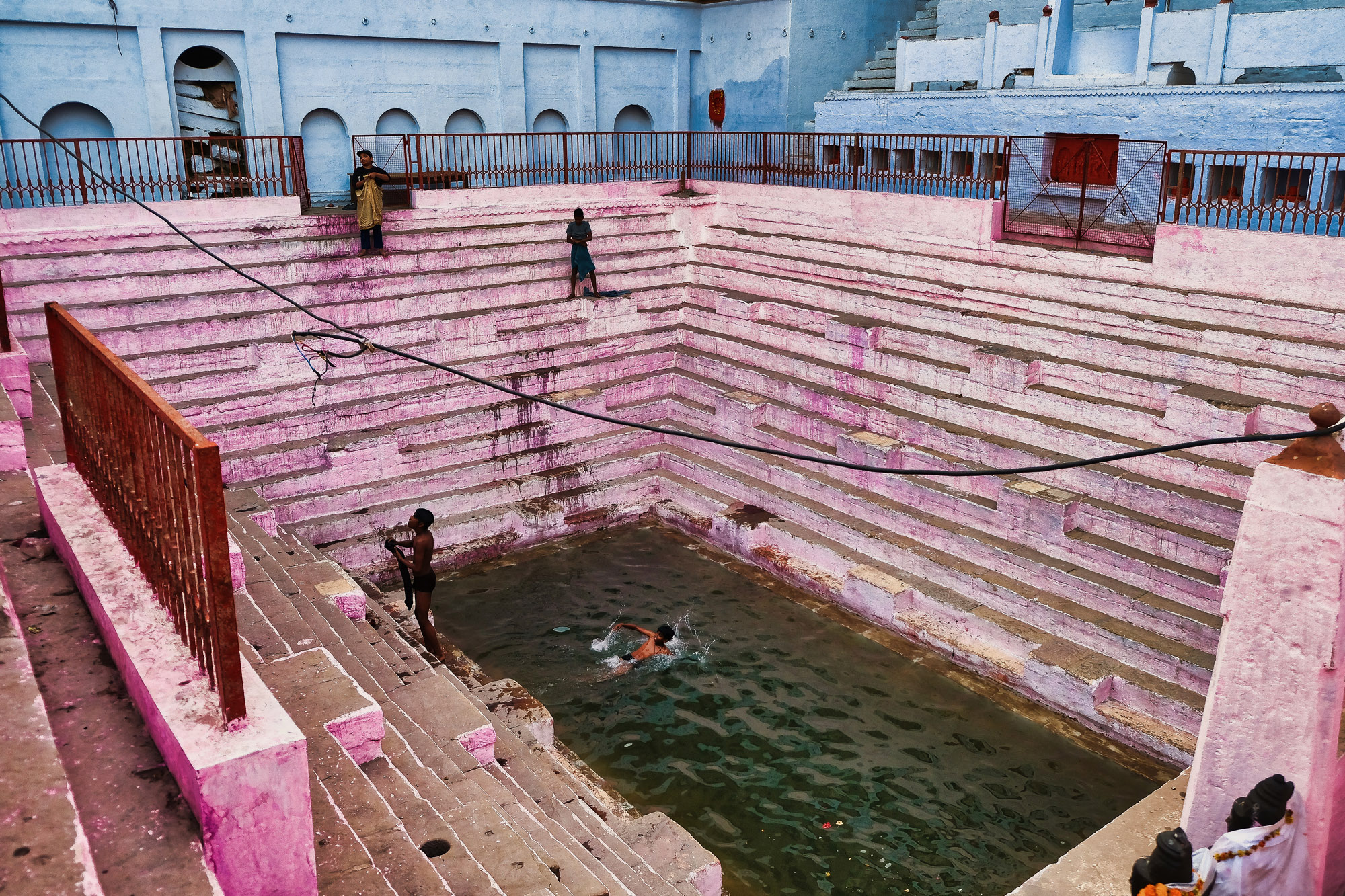 Vasca sacra con i gradini rosa e i nuotatori, Varanasi, Uttar Pradesh, India